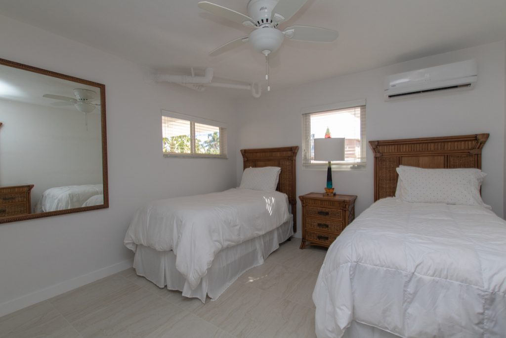 twin beds with clean crisp white linen and rattan furniture